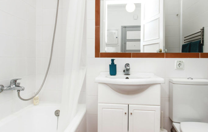 Bathroom with bathtub and a big wall mirror at the apartment in Algés Portugal